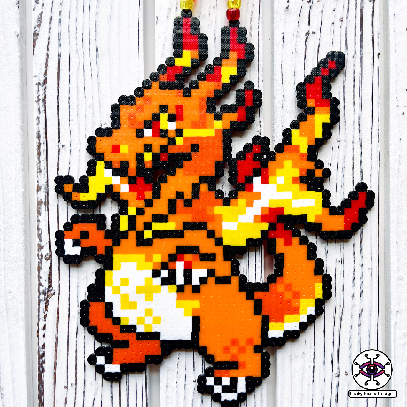 Gigantamax charizard perler necklace by leaky pixels. orange pokemon dragon with fire emitting from its body.