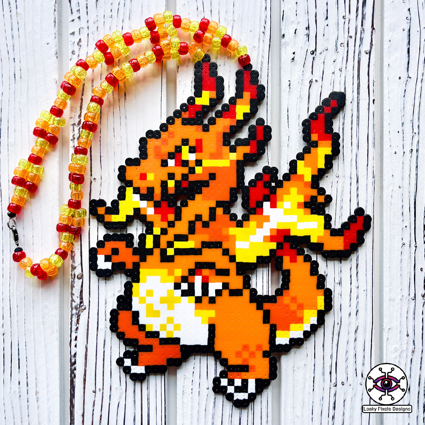 Gigantamax charizard perler necklace by leaky pixels. orange pokemon dragon with fire emitting from its body.