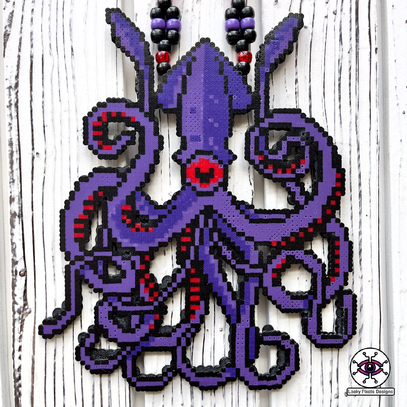 Dark purple kraken perler necklace with red eye and suckers. mysterious and dark. necklace is made of purple, black, red, silver and clear pony beads. high detail and quality.