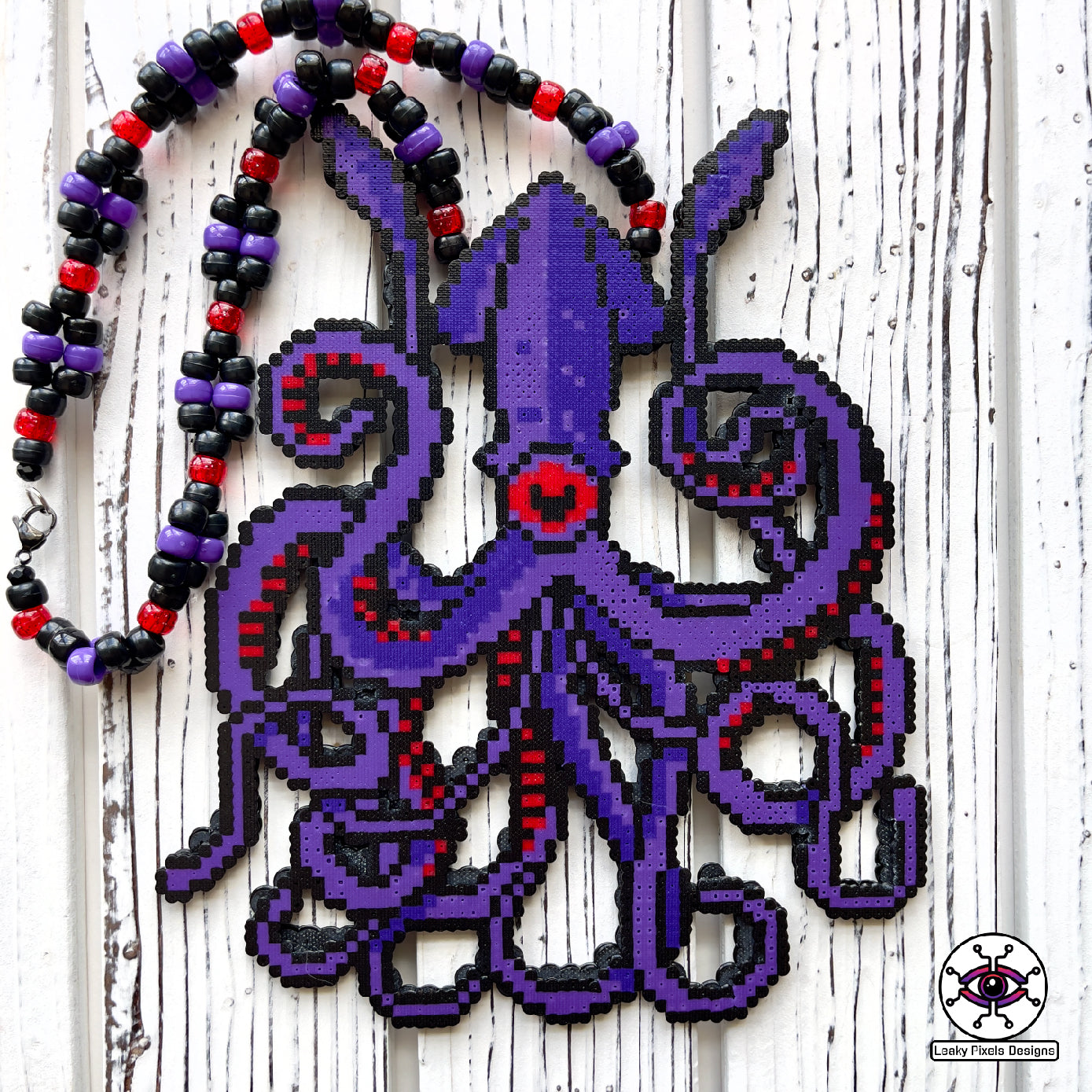 Dark purple kraken perler necklace with red eye and suckers. mysterious and dark. necklace is made of purple, black, red, silver and clear pony beads. high detail and quality.