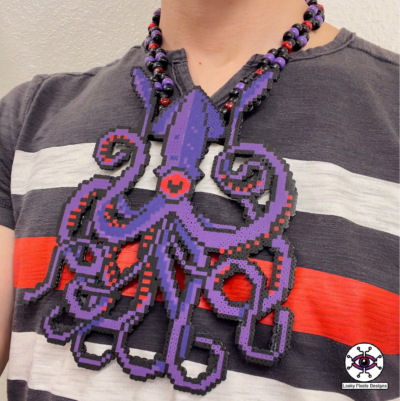 Dark purple kraken perler necklace with red eye and suckers. mysterious and dark. necklace is made of purple, black, red, silver and clear pony beads. high detail and quality.