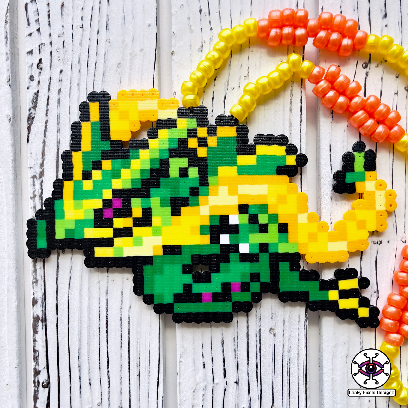 mega rayquaza pokemon perler necklace. green dragon with yellow and orange tendrils flying beside its body. pony beads make up the necklace.